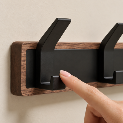 Close-up of the Whare Dual Hook's black metal hook and timber rail, a finger pressing to show the hook's give — Wood Store NZ