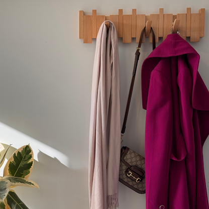 Beech Piano Hook rack on a hallway wall holding a scarf, a handbag and a wool coat. Wood Store NZ